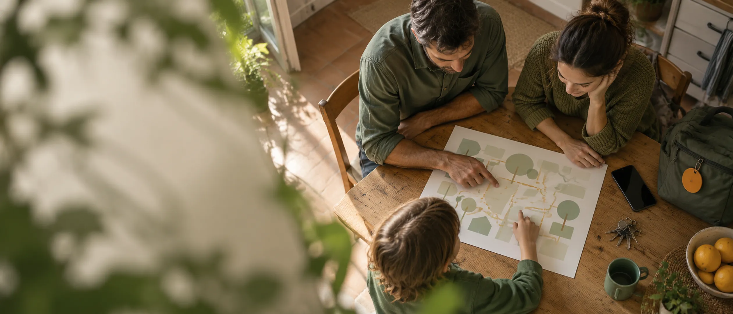Manos de una familia ordenando un plan impreso sobre la mesa de la cocina, junto a una mochila con etiqueta ámbar.